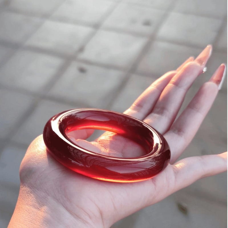 A glossy deep red jade bangle bracelet for women with a classic round style featuring a smooth polished surface and subtle internal marbling.