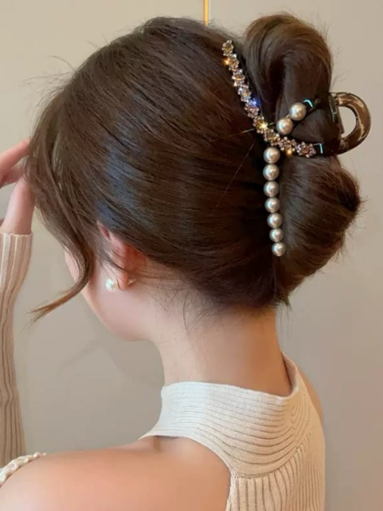 Barrette serre-cheveux en forme de pince à perles imitation nacrées, ornée d’un design courbé élégant, rehaussé de cristaux étincelants et d’une rangée verticale de perles blanches.