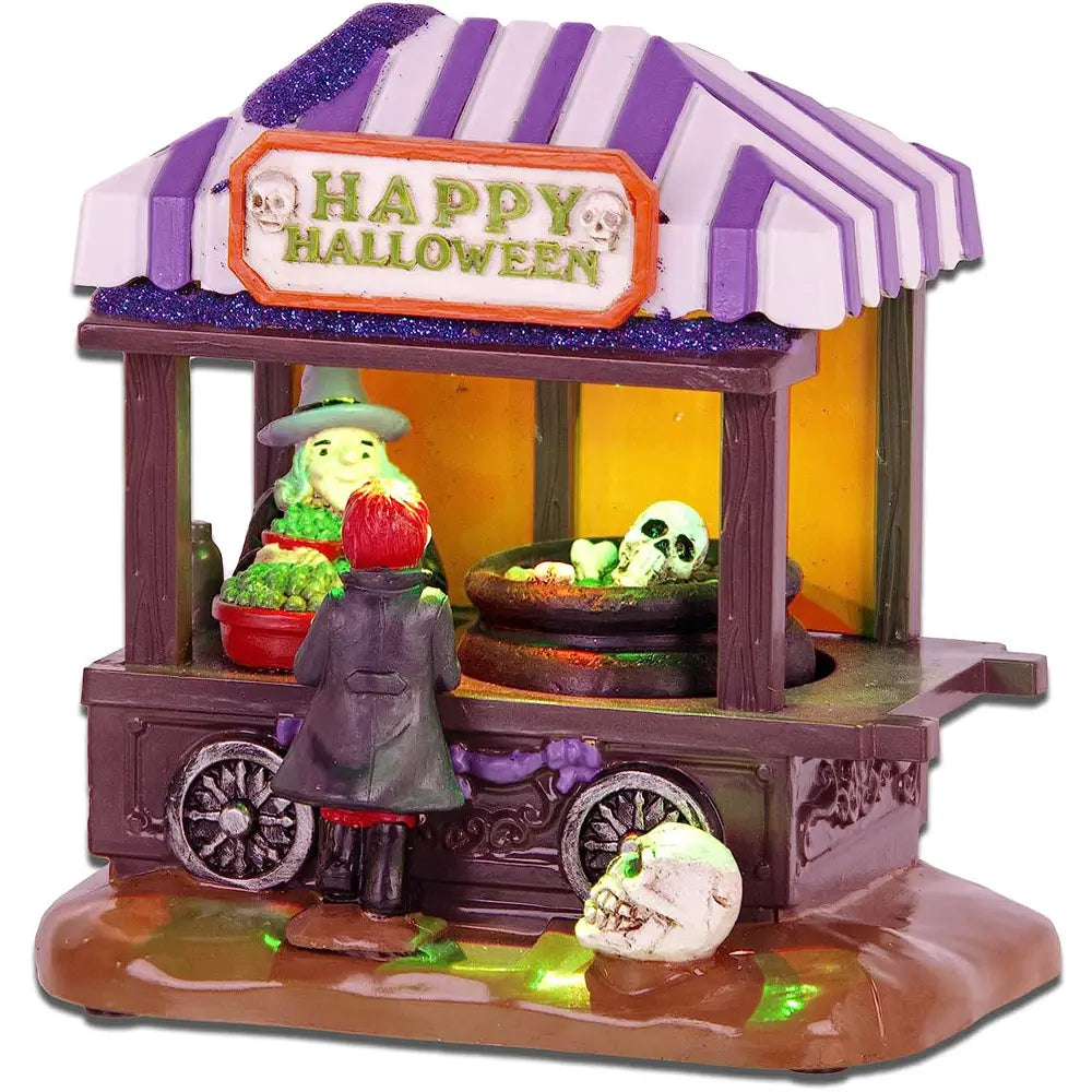 Auvent rayé violet et blanc avec bordure scintillante au-dessus d’une enseigne joyeuse d’Halloween, présentant des figurines miniature de vendeuse et de cliente sorcière dans un charriot d’exposition en pot à soupe roulant en bois brun foncé, décoration Halloween 5 x 14 cm.