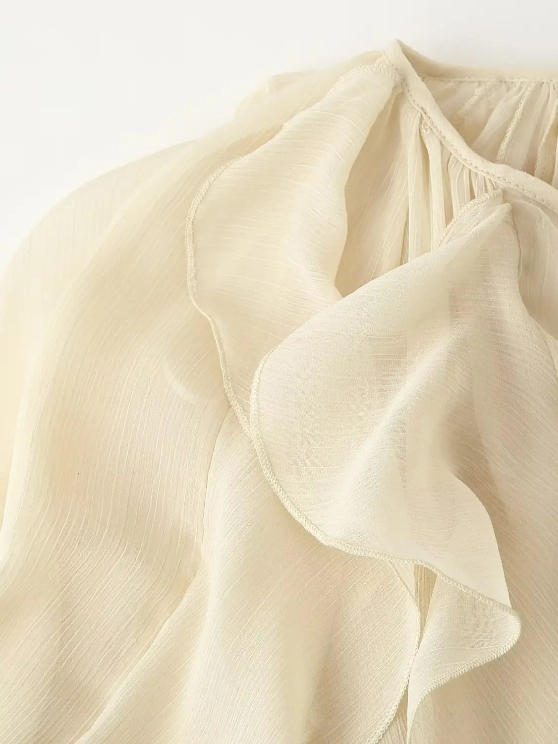 Cream-colored long sleeve ruffle shirt long chiffon blouse with delicate ruffled detailing at the neckline.