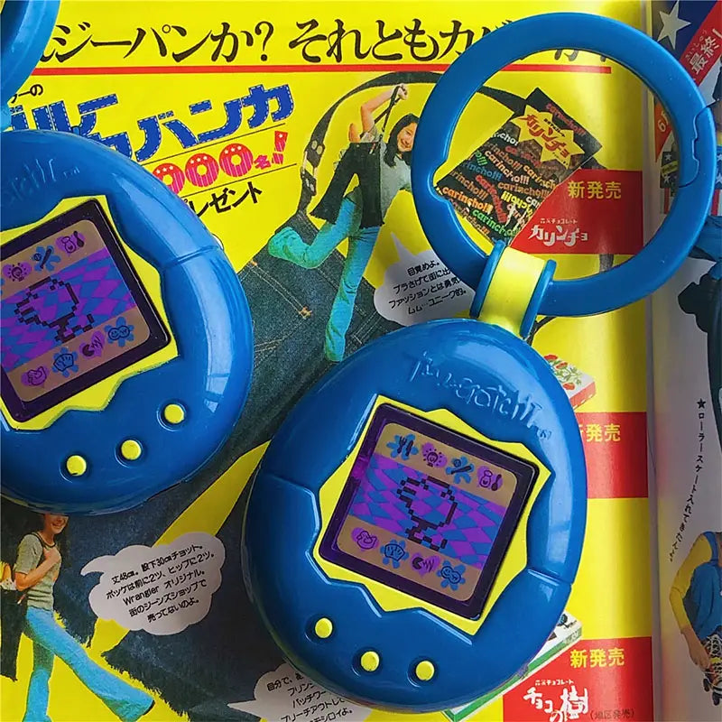 Blue tamagotchi electronic virtual pet keychain 90s toy with a yellow-bordered screen displaying pixelated creatures.