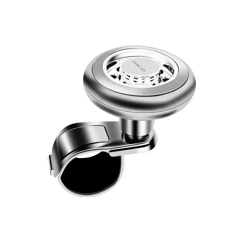 Gira-volante metálico plateado con rotación de 360 grados y agarre de goma negra, diseñado para un ajuste universal en volantes de dirección de automóviles.