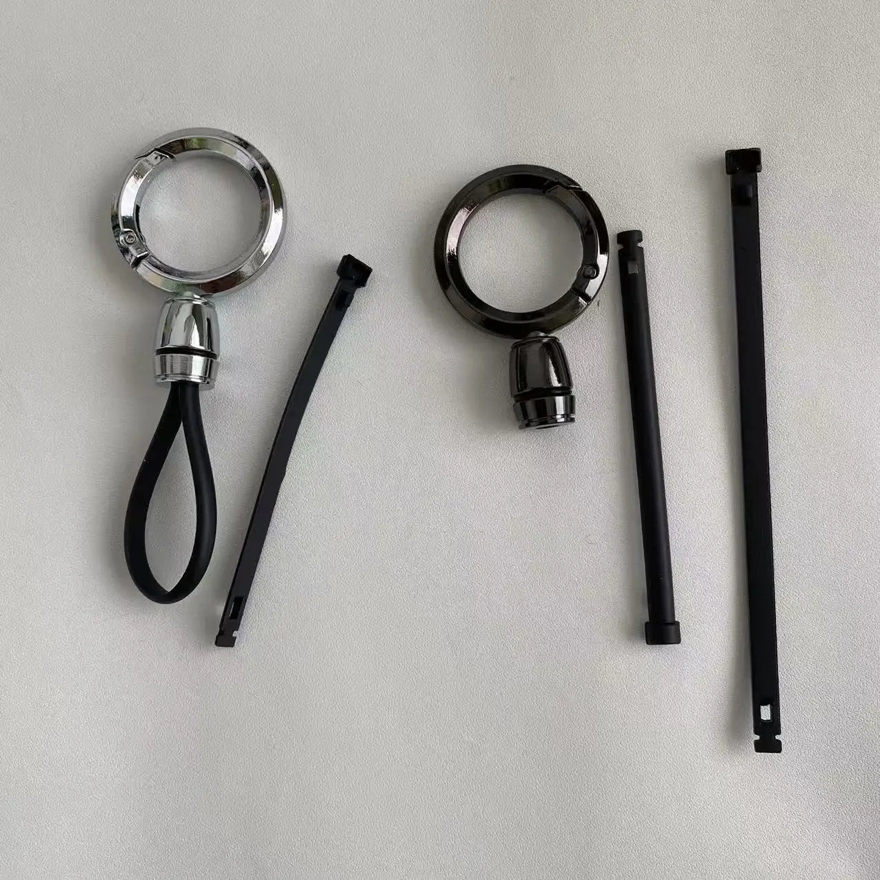 Soportes portallaveros de mosquetón magnético de metal con acabado cromado y negro, con correas de agarre recubiertas de goma para uso anti-pérdida.