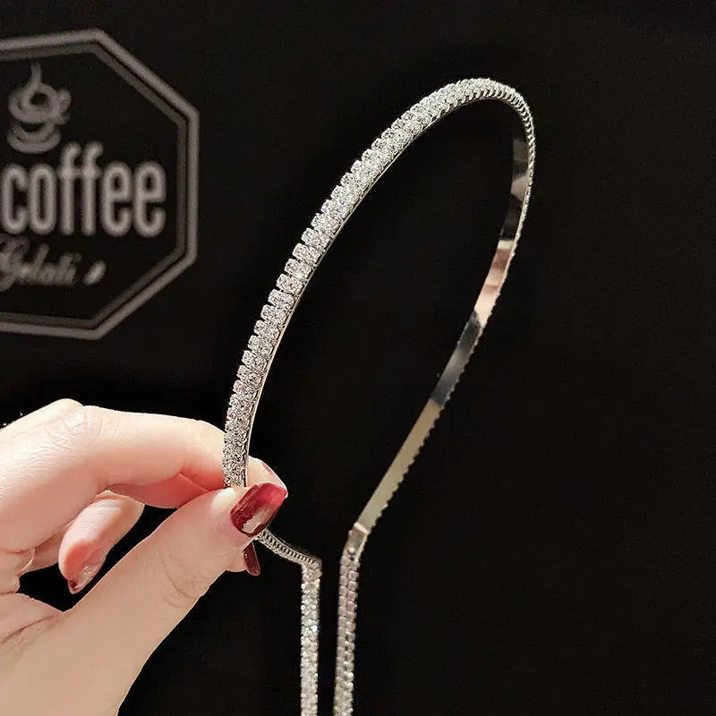 A sleek silver-toned crystal rhinestone tassel headband for women adorned with a continuous row of sparkling clear crystals along its curved edge.