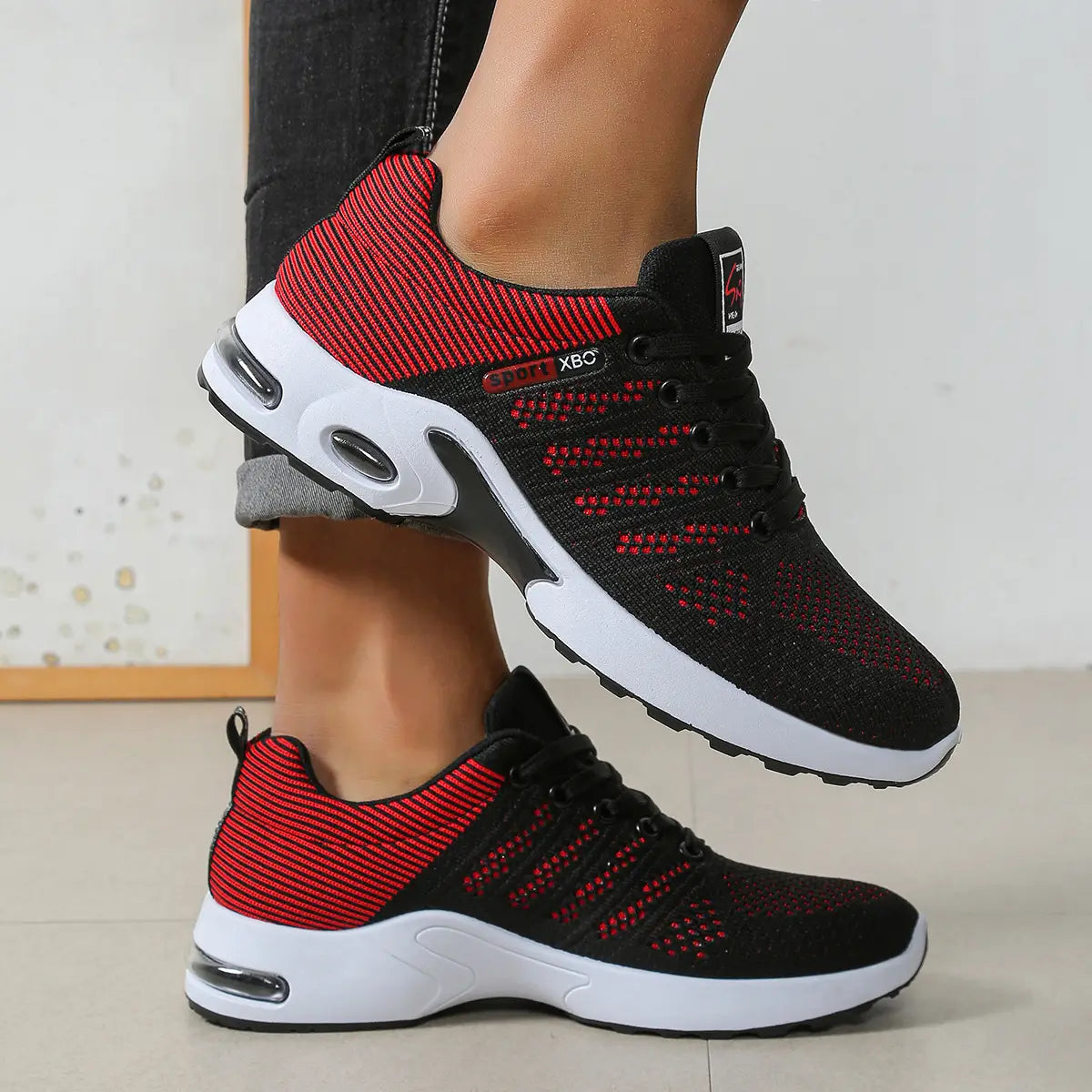 Baskets décontractées pour hommes en maille, en noir et rouge, avec des semelles blanches et des unités de coussin d’air transparentes.