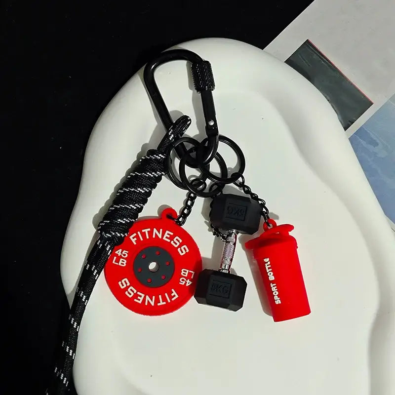 Porte-clés de musculation rouge et noir comprenant une plaque de poids de 45 lb, un haltère et une breloque de bouteille shaker, conçu comme accessoire de cadeau.