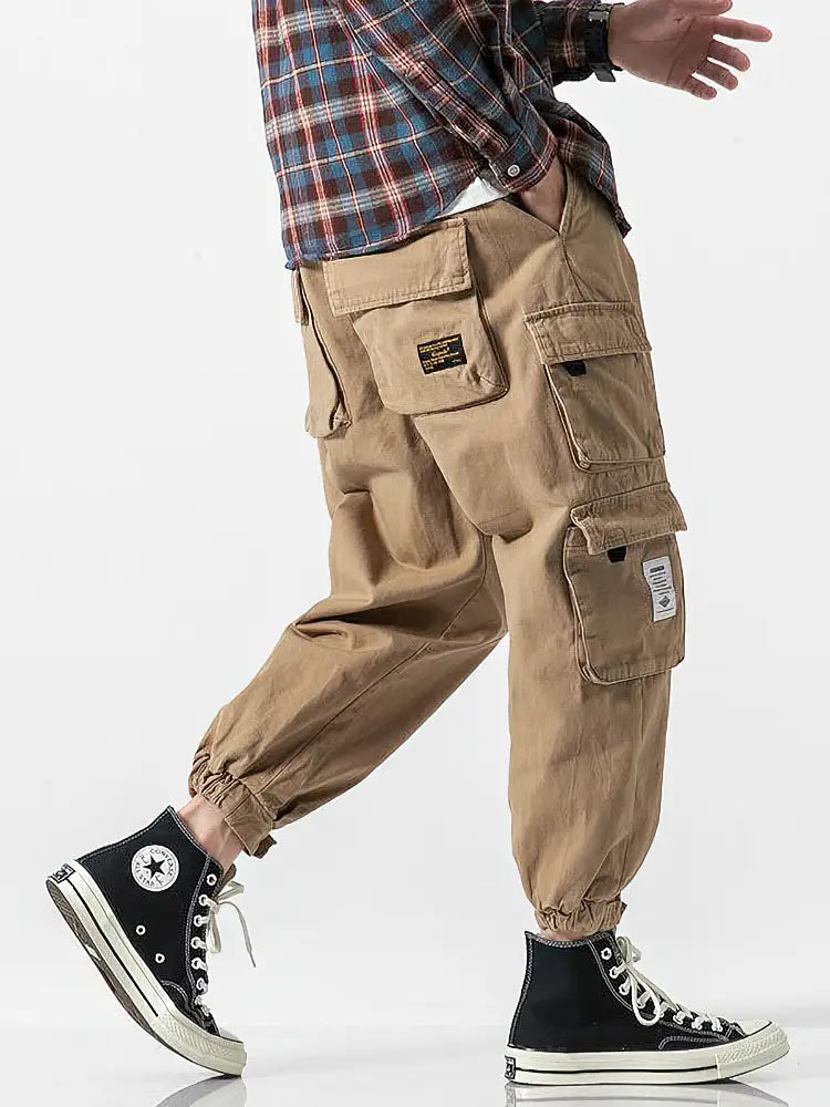 Pantalon jogger cargo coréen beige pour hommes, doté de plusieurs poches et de patchs de tissu, conçu comme un pantalon décontracté ample.