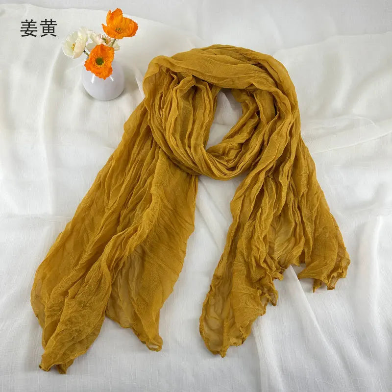 Écharpe en coton et lin plissé jaune moutarde, avec une texture froissée douce et un tissu léger et transparent.