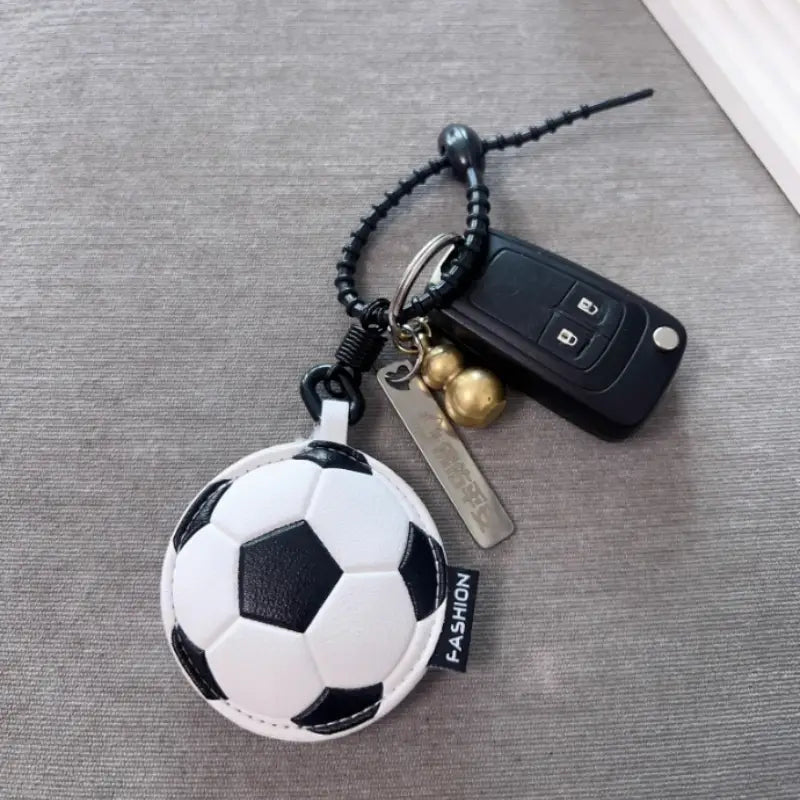 A white and black soccer ball-shaped leather sports ball keychain with a stitched leather-like texture used as a bag charm.