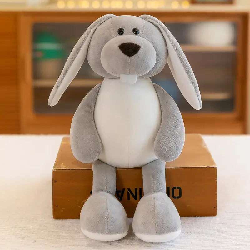 Lapin en peluche gris doux, avec de longues oreilles pendantes, yeux à boutons noirs, nez brun foncé et touches blanches sur le ventre et les pattes, présenté parmi les animaux en peluche rembourrés, lion éléphant tigre de la forêt