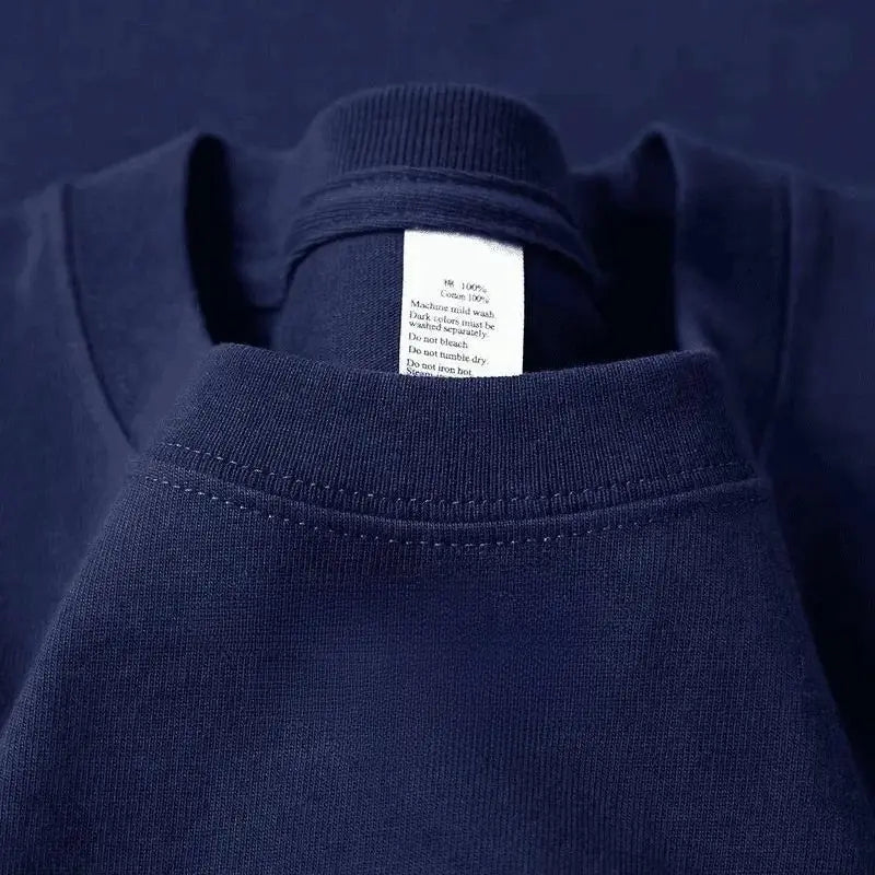 Camiseta de algodón de cuello redondo color azul marino con una etiqueta de cuidado blanca cosida en el interior del cuello.