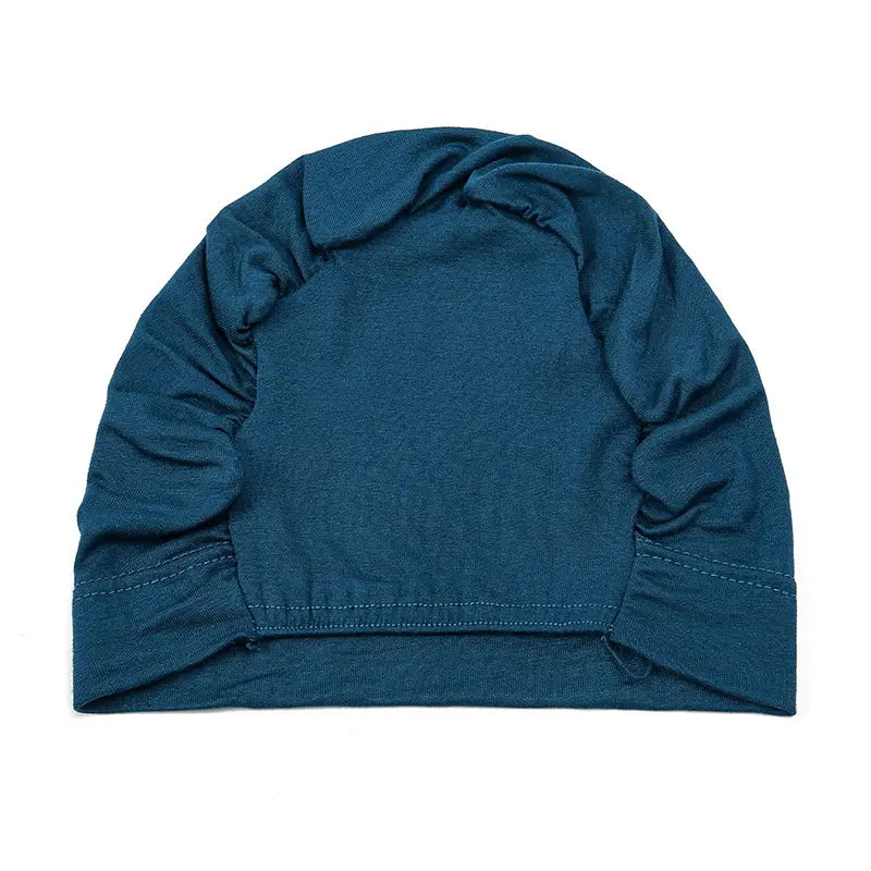 a stretchy jersey hijab cap and turban set featuring a soft teal-colored knit beanie with slightly textured fabric and gathered cuffs