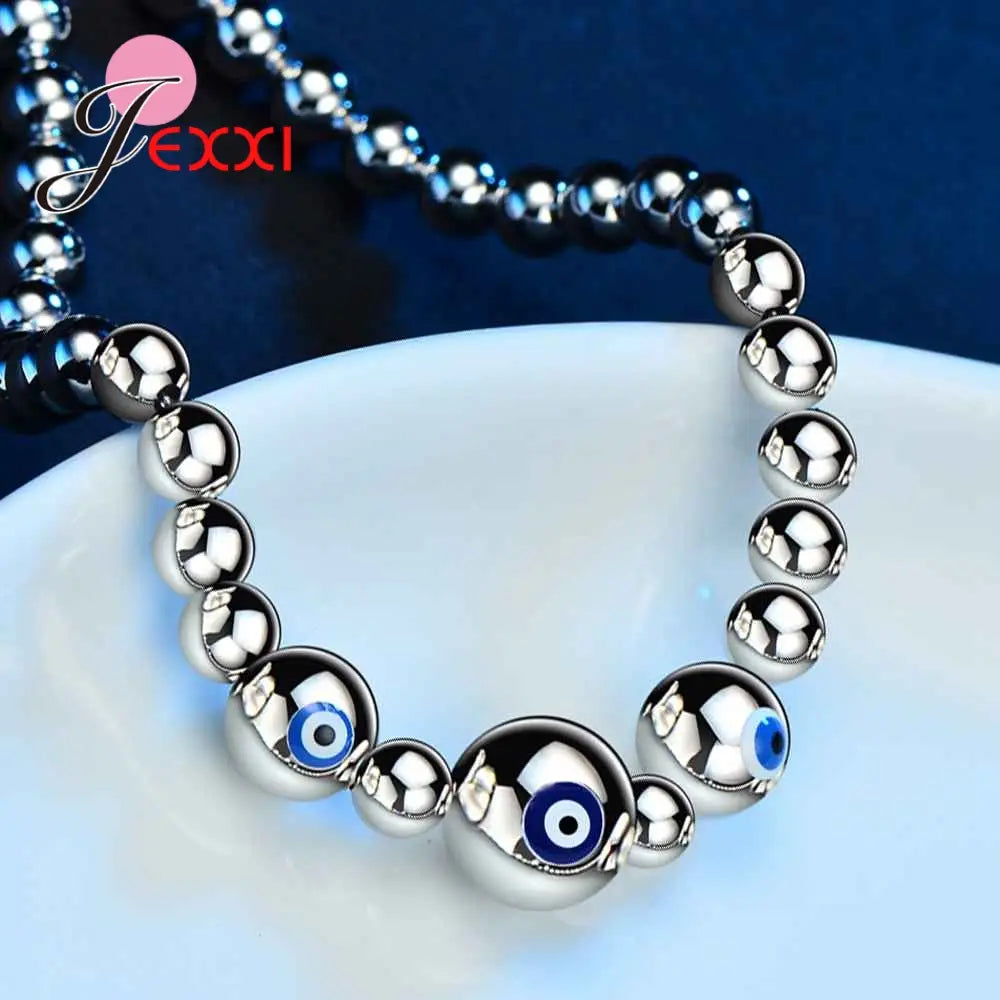 Sterling silver evil eye charm bracelet for women featuring polished silver beads and two prominent blue evil eye charms.