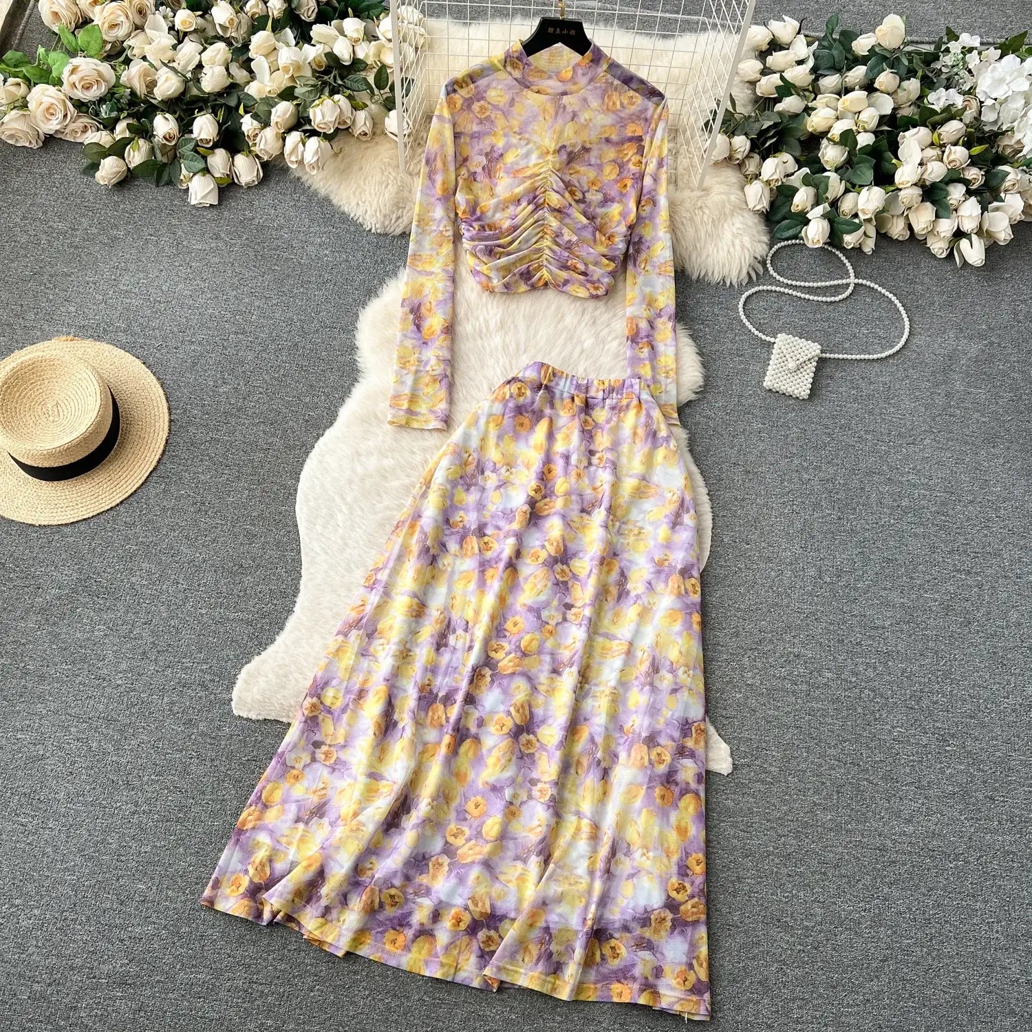 a two-piece mesh skirt set in soft purple and yellow floral pattern featuring a ruched high-neck top with long sleeves and elastic closure