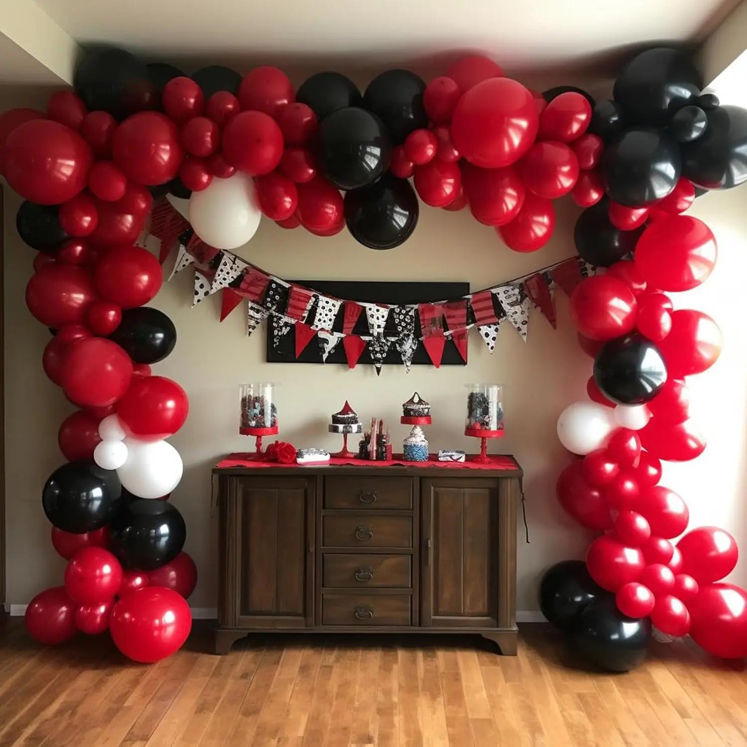 Un kit festivo de arco de globos rojo, negro y blanco con 98 piezas, con un letrero decorativo colgante debajo del arco.