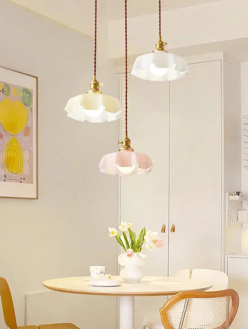 Trois luminaires suspendus délicats à jupe florale en verre avec tête de lampe en cuivre, suspendus dans des tons pastel blanc et rose, avec cordons tressés et supports en laiton.