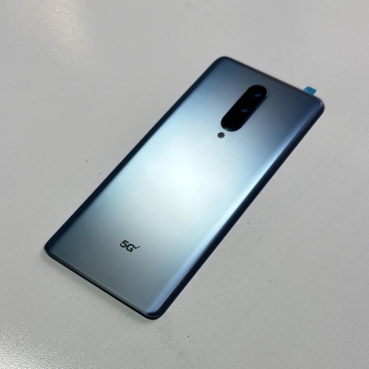 die Rückseitenverkleidung eines eleganten blauen Oneplus-8-Smartphones mit einem vertikalen Kameramodul und einer Akkufachabdeckung aus hochwertigem Gorilla-Glas für einen verbesserten Schutz, einschließlich des 5G-Logos