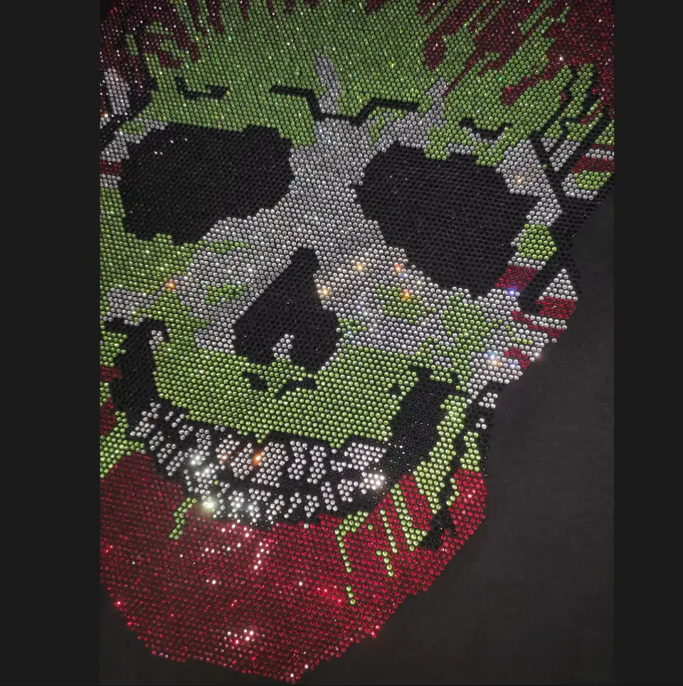 Men rhinestone devil bear graphic tee featuring a sparkling green and red rhinestone skull patch with black eye sockets silver nose bridge accents and a dripping design.