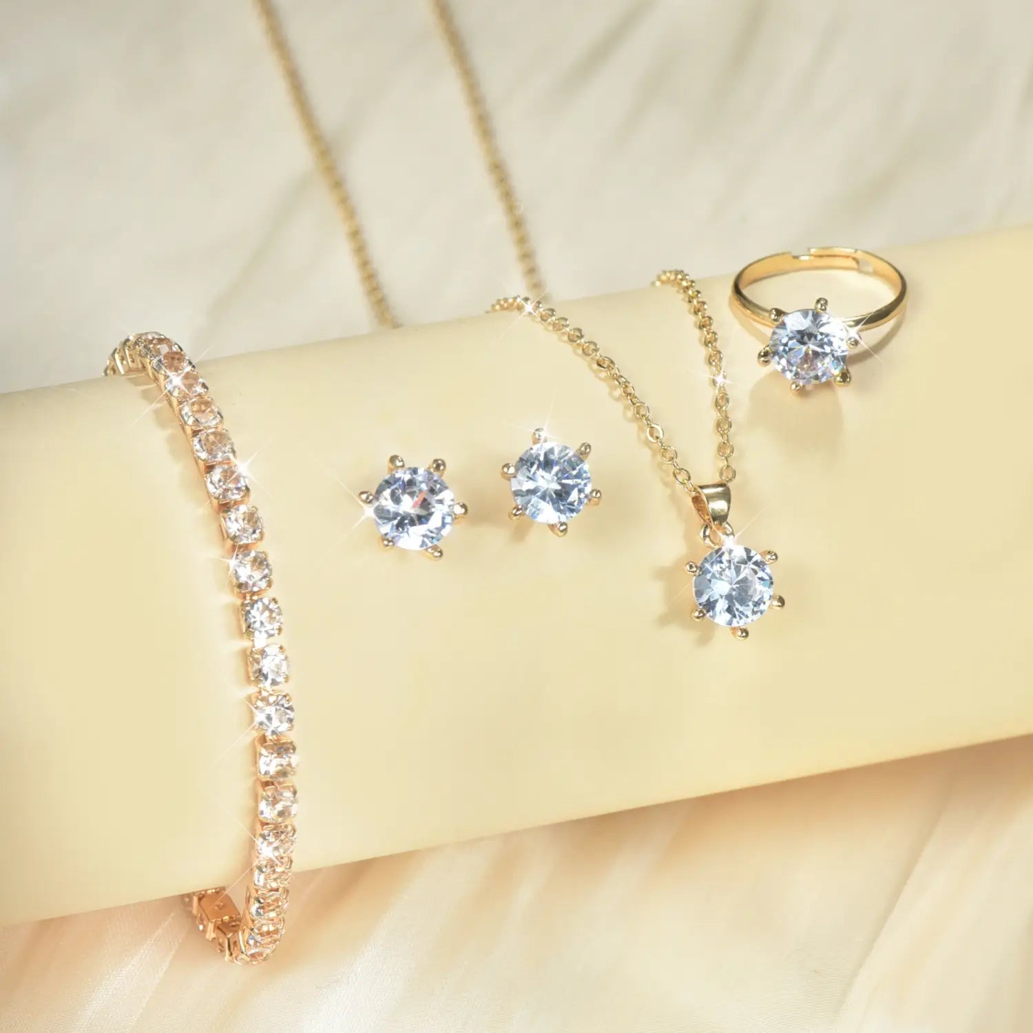 Juego de joyería de 5 piezas con circonitas cúbicas de color dorado, que presenta una pulsera, aretes, collar y anillo adornados con piedras de circonita cúbica transparentes.