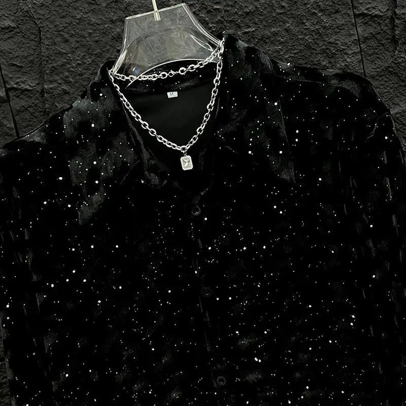 Camisa de hombre negra de terciopelo con lentejuelas, de manga larga, adornada con lentejuelas brillantes, mostrada en una percha de plástico transparente.
