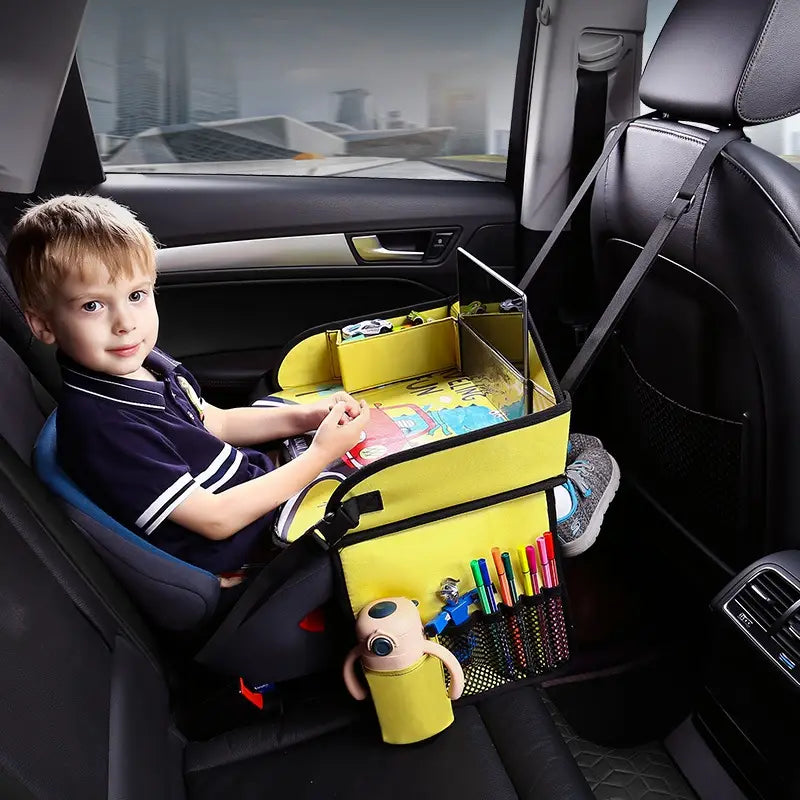 Gelber Kindersitz-Reisetablett-Organizer für das Auto aus Stoff mit mehreren Fächern und Netz-Taschen, die Buntstifte, ein Plüschtier und andere Gegenstände für Kinder aufnehmen.