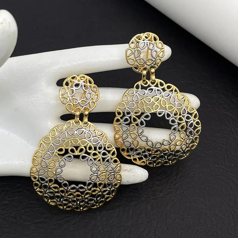Boucles d’oreilles pendantes en filigrane bicolore or et argent, avec des motifs circulaires complexes, provenant d’un ensemble de bijoux pour femmes.