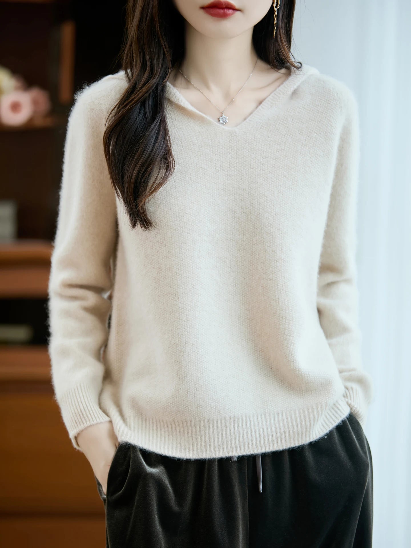 Cream-colored pure wool v-neck hooded pullover sweater with soft knit texture and ribbed cuffs and hem.