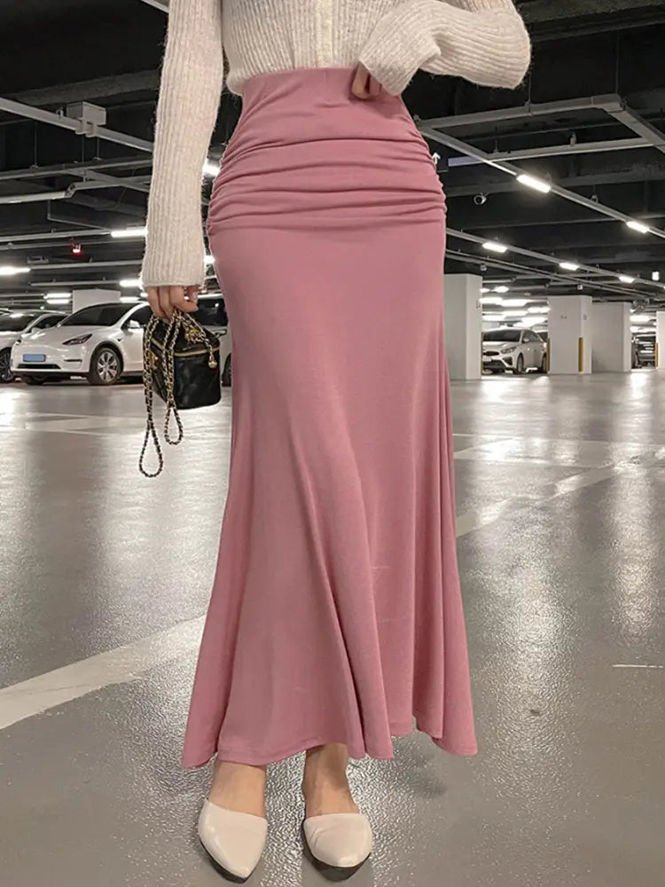 Ein zarter rosafarbener Meerjungfrauen-Midirock mit geraffter, hoher Taille, fließendem Stoff und einer figurbetonten Bundlösung.