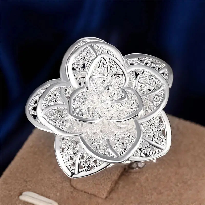 Parure de bijoux floraux en argent sterling comprenant une bague en forme de fleur en argent avec un motif de filigrane complexe et des cristaux transparents sertis.