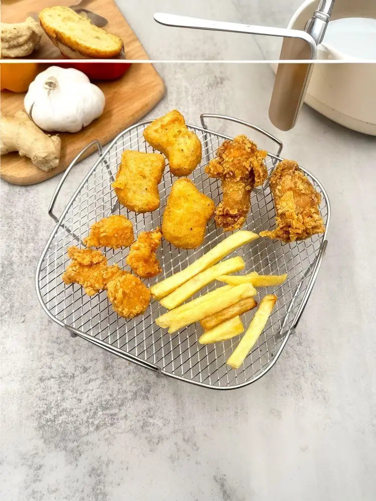 Edelstahl-Luftfritteusen-Grillrost als stapelbarer Korb, dargestellt als Korb aus silbernem Drahtgeflecht mit Griffen, die goldbraune Stücke von gebratenem Hähnchen und Pommes frites enthalten.