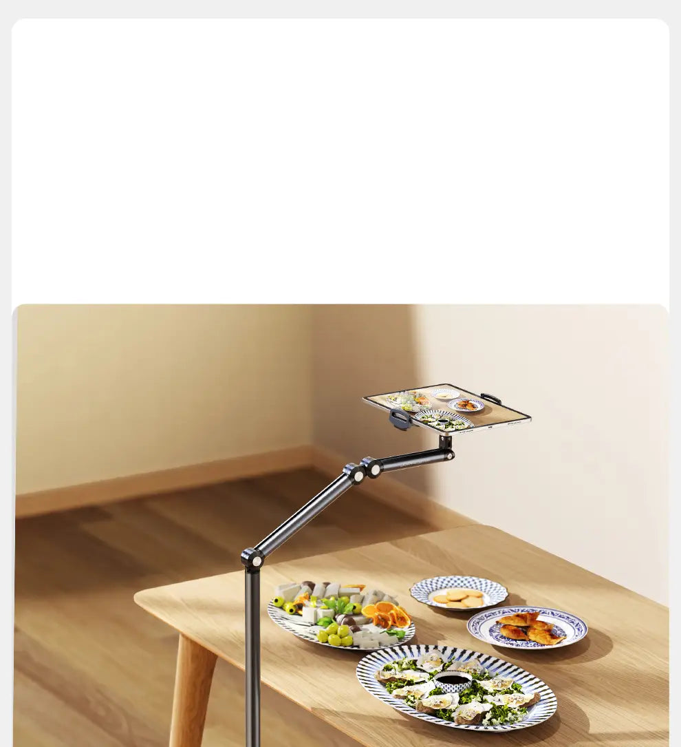Black aluminum alloy adjustable tablet and phone floor stand holding a smartphone over a wooden table with plates of food.