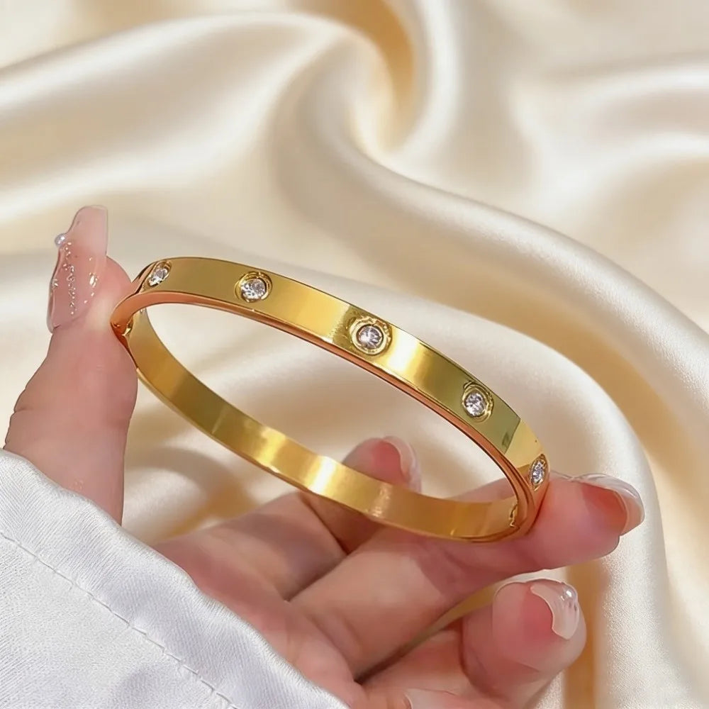 Stainless steel gold-toned bangle bracelet for women featuring five clear round gemstones in a sleek minimalist design.
