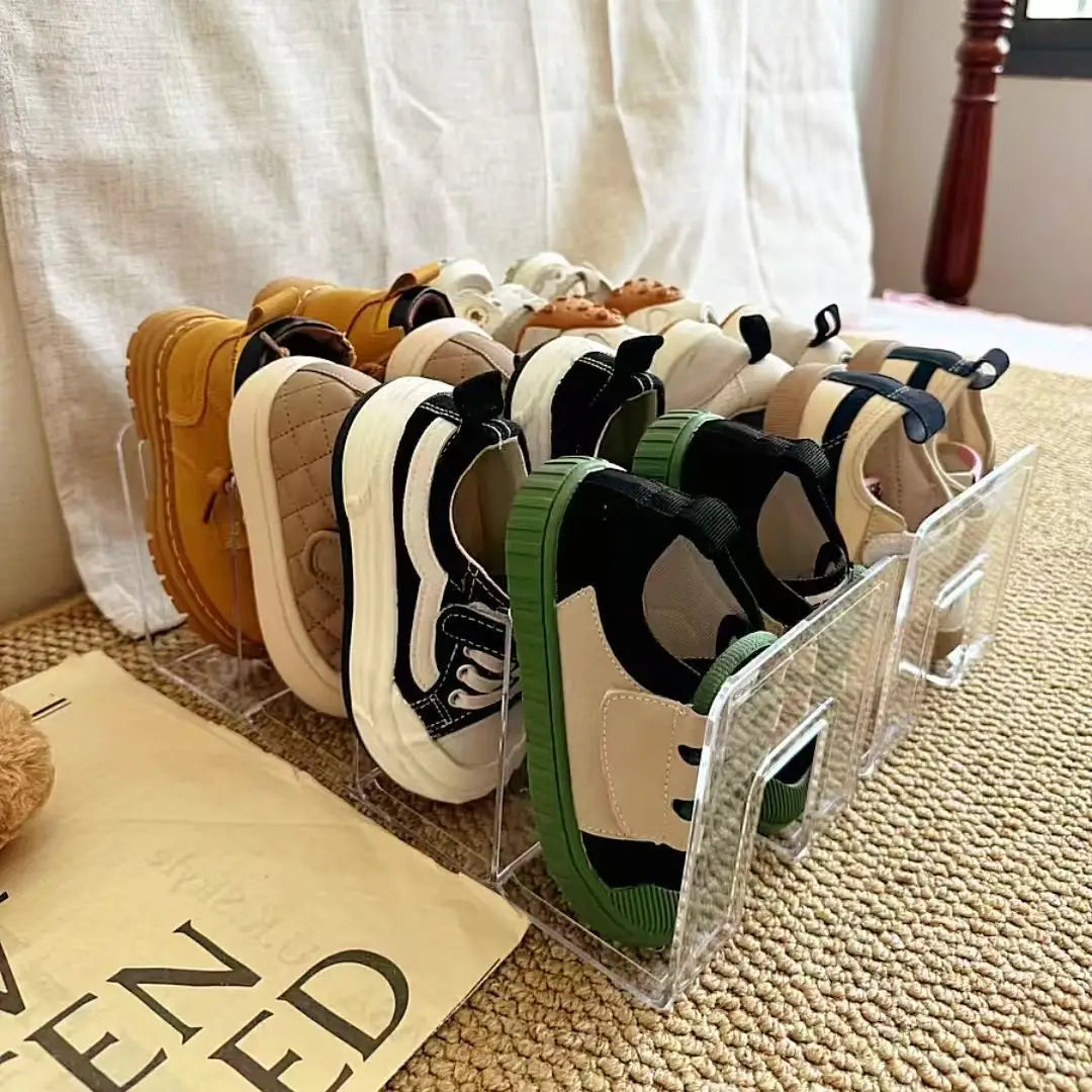 durchsichtiger Acryl-Baby-Schuhaufbewahrungsständer zur Anordnung, der bunte Kindersneaker in einem transparenten Acrylhalter zeigt.