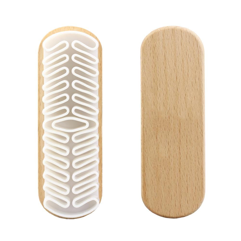 Cepillo de limpieza para interior de coche de ante Alcántara con mango de madera clara, cabeza de cerdas de goma blanca con textura e integrada mediante un patrón entrelazado.