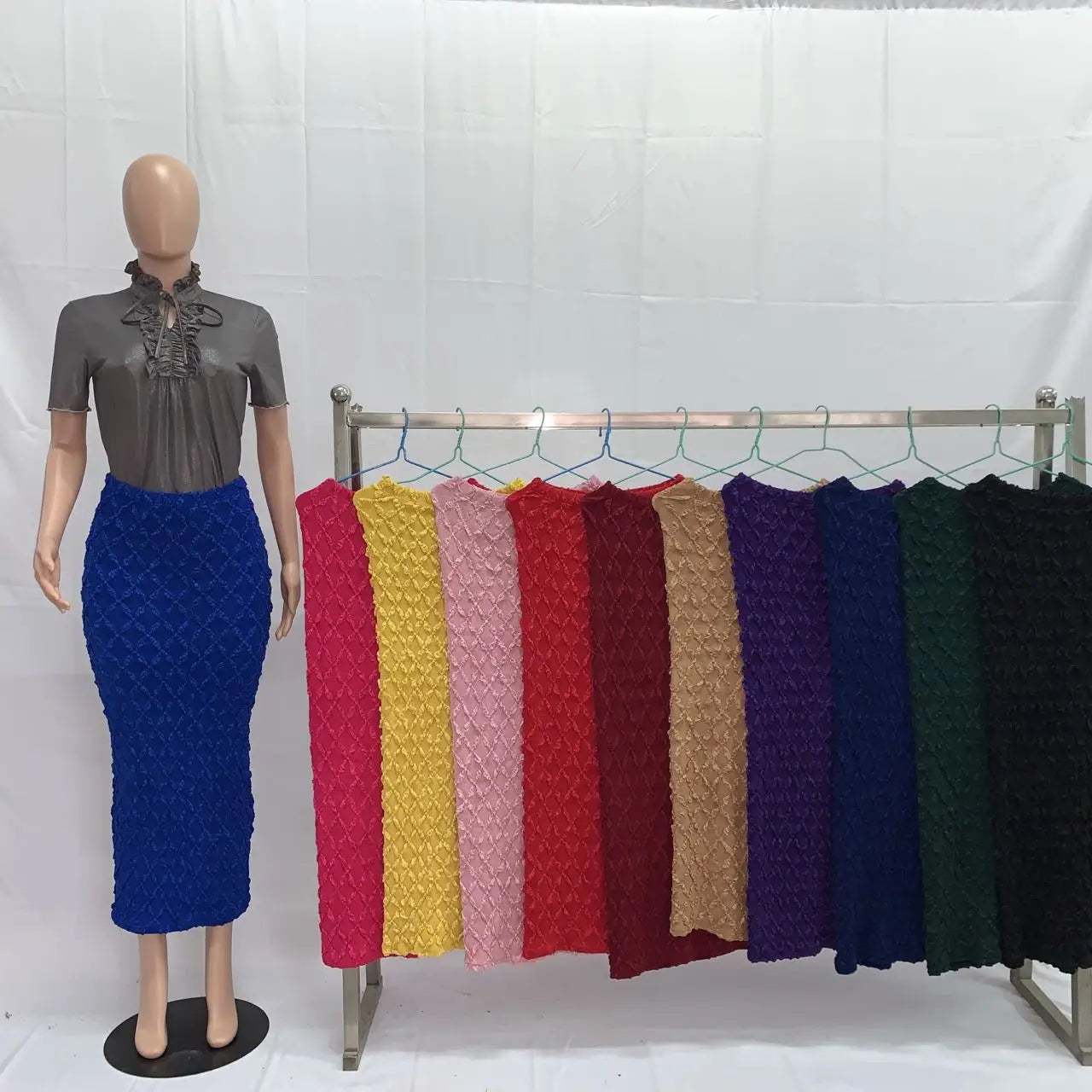 A mannequin wears a fitted high waist knit midi skirt in blue with a textured crisscross pattern.