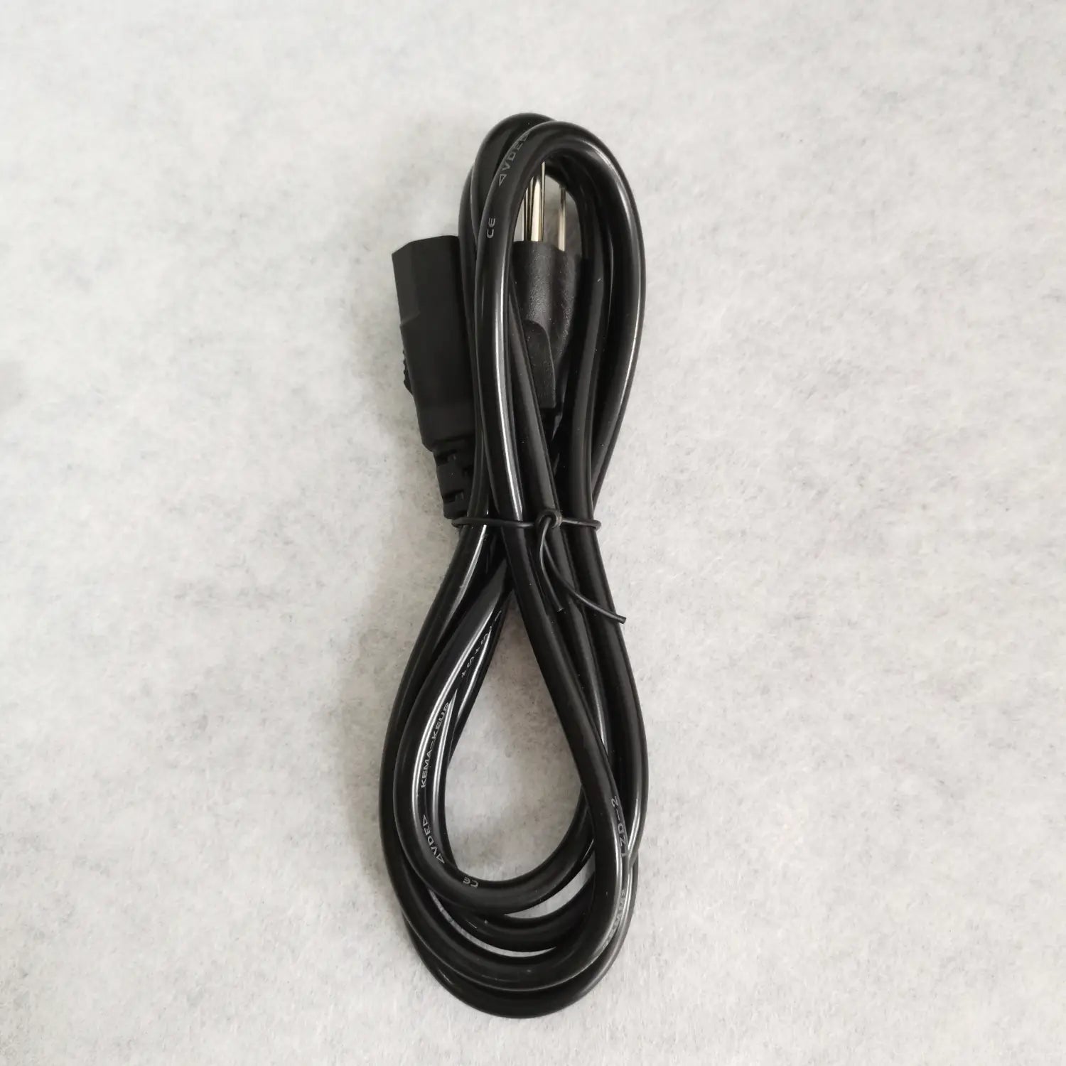 Schwarzes Netzkabel mit dreipoligem Stecker und rechteckigem Anschluss, ordentlich auf einer hellen Oberfläche gewickelt, für das Netzteil des Signal Fire Fusion Splicer 12 V 8 A.
