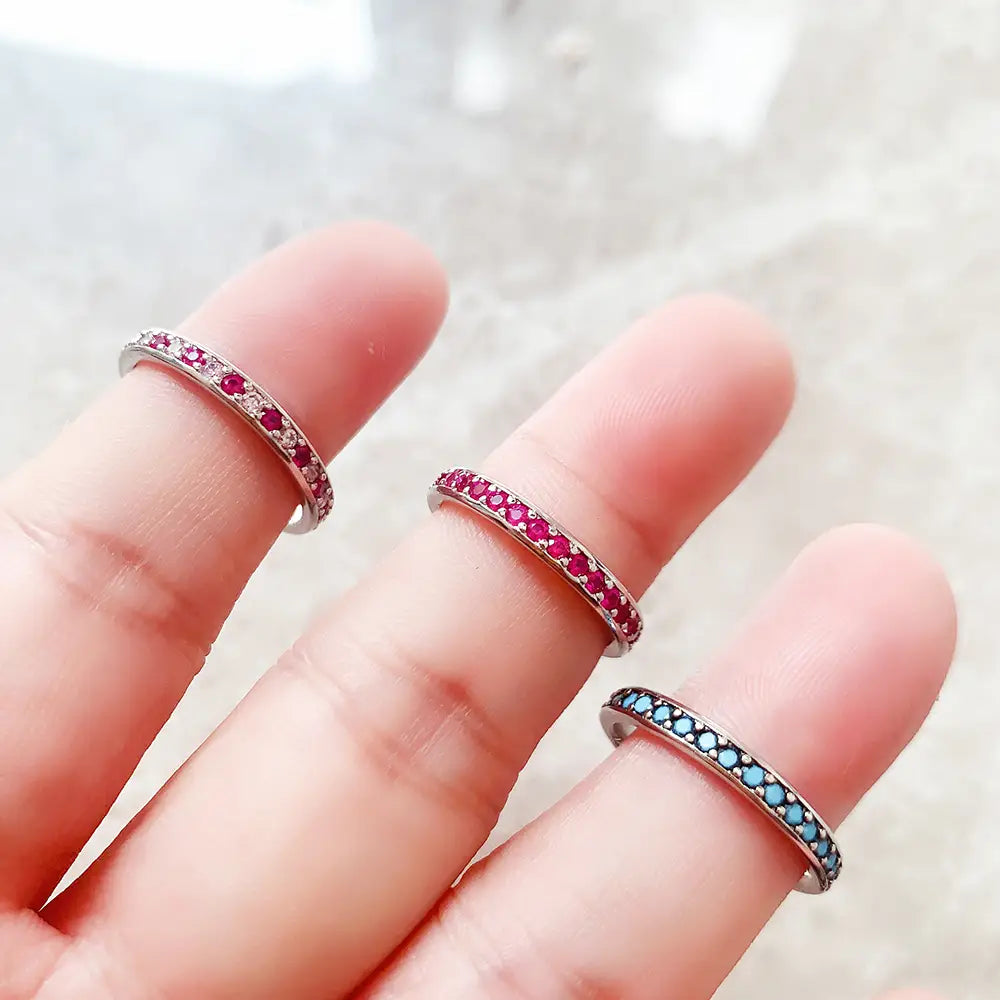 Bague empilée en argent sterling sertie d’une pierre précieuse, comportant trois fines bandes délicates, ornées de rubis rouges vibrants et de pierres bleu clair, serties dans un argent élégant.