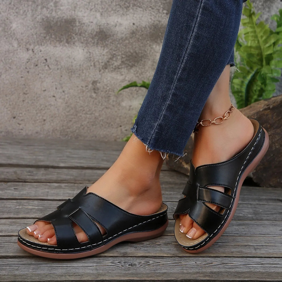 Black leather women’s platform wedge slide sandals with a comfortable cushioned sole and white stitching along the edges for summer footwear.