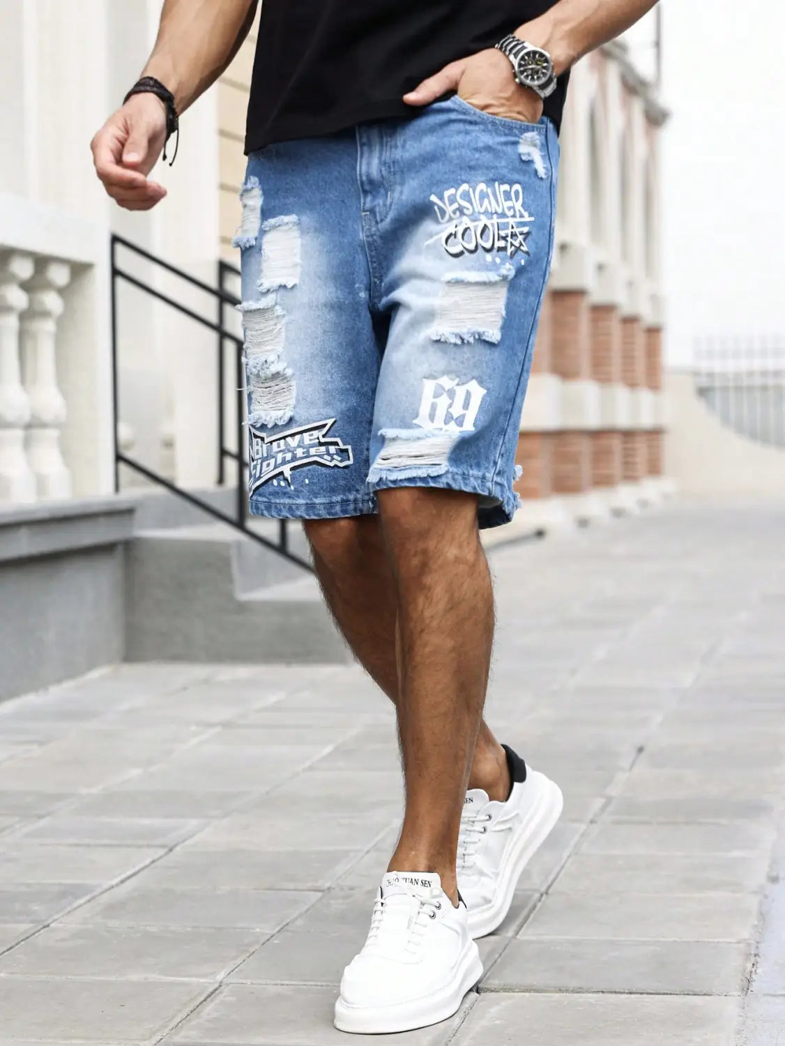 Shorts en jean bleu déchirés pour hommes, présentant des patchs abîmés, une typographie blanche style graffiti et un motif « 69 » à l’avant, pour une tenue d’été.