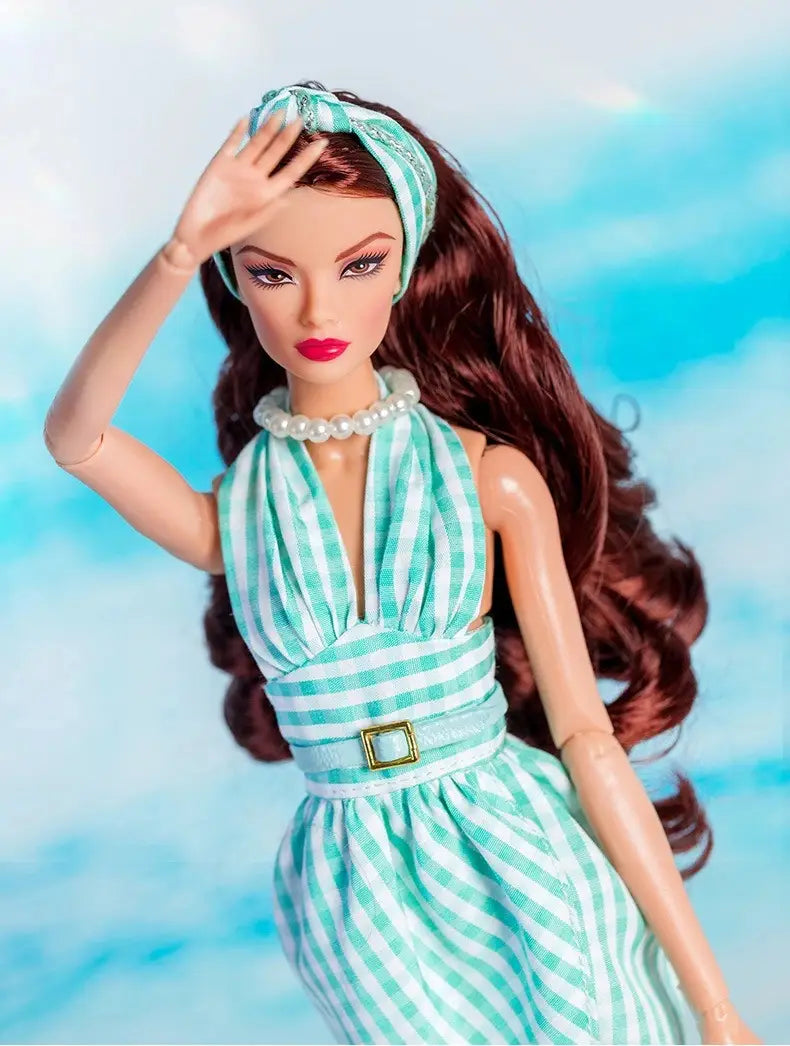 Ensemble de vêtements et d’accessoires de mode pour poupée à l’échelle 1/6, comprenant une poupée Barbie portant une robe salopette à bretelles en rayures vert menthe et blanc, avec une ceinture à boucle dorée, accompagné d’un serre-tête assorti et d’un collier de perles.