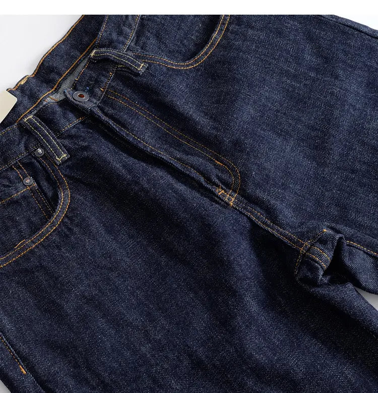 Heavyweight red selvedge denim jeans in dark indigo with contrasting tan stitching and metal buttons.