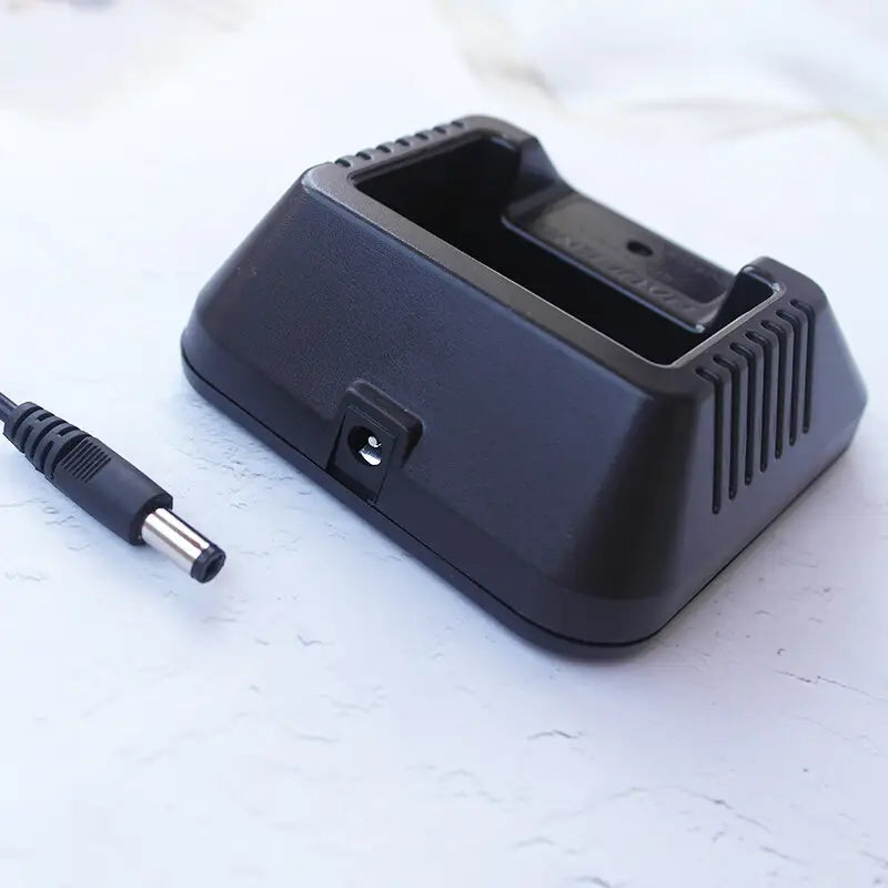 バオフェンの携帯型トランシーバー用の黒色プラスチック製デスクトップ充電器で、USB充電ケーブルおよび対応する電源アダプタを付属しています。