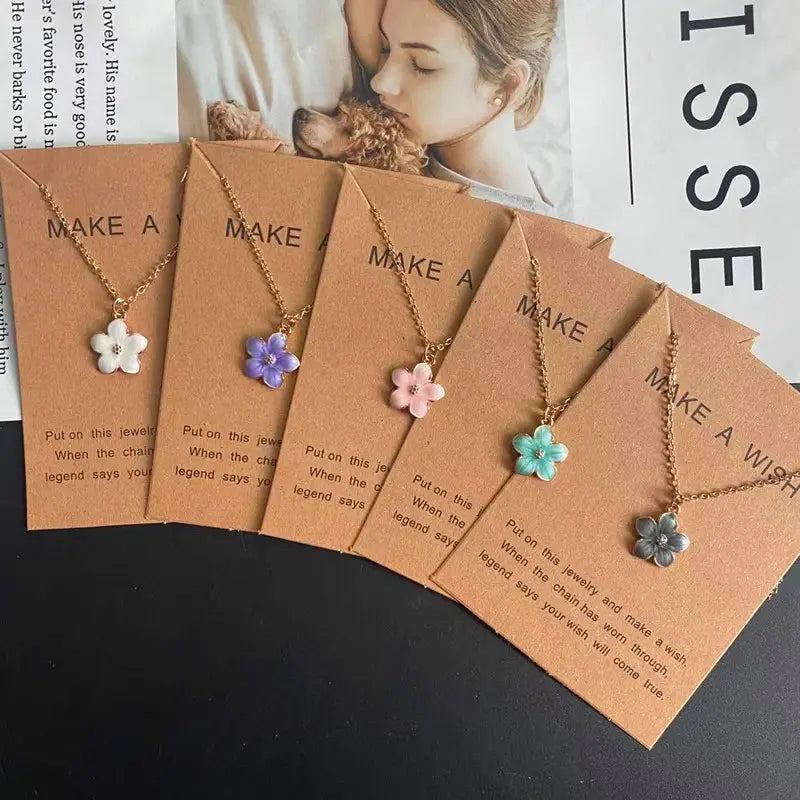 Un collier délicat en chaîne à maillons en or, arborant un pendentif de fleur romantique à cinq pétales, en blanc, violet, rose, turquoise et argent.