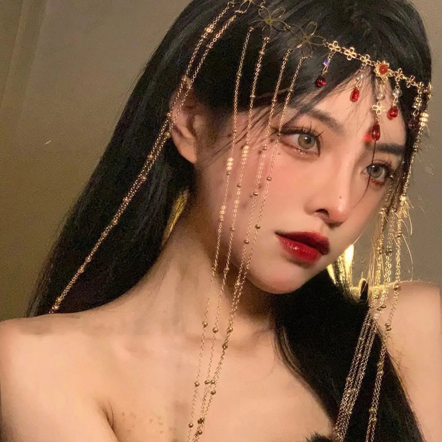 赤い宝石のゴールド前髪チェーンヘアペンダント。繊細な花のデザインと赤い宝石のアクセントをあしらったゴールドトーンのチェーンヘッドピースが特徴です。