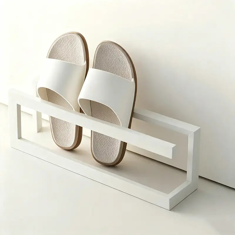 Weißes freistehendes Metall-Schuhregal mit minimalistischem Design, das ein Paar weiße und beigerfarbene Schlupf-Sandalen für platzsparende Lagerung hält.