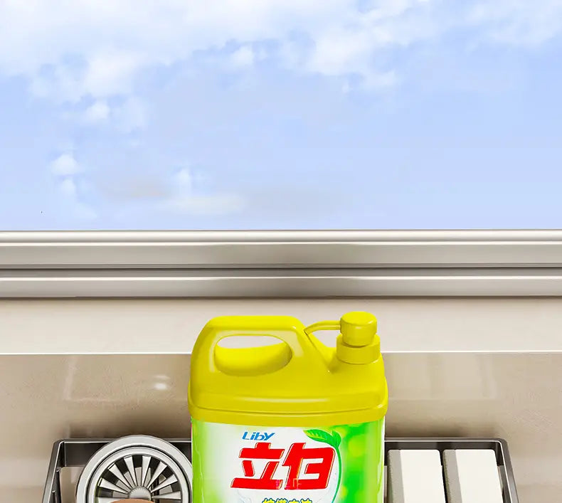 Botella de plástico amarilla brillante de líquido lavavajillas Liby, con etiqueta verde y caracteres chinos rojos, colocada dentro de un organizador para fregadero de cocina de acero inoxidable.