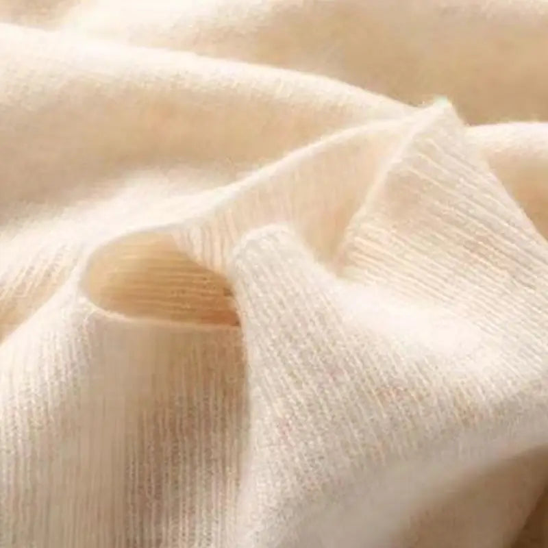 Cremefarbener gerippter Strickstoff aus Wolle mit einer weichen, strukturierten Oberfläche, verwendet für einen Strickschal, Cardigan oder Wickel aus Wolle.