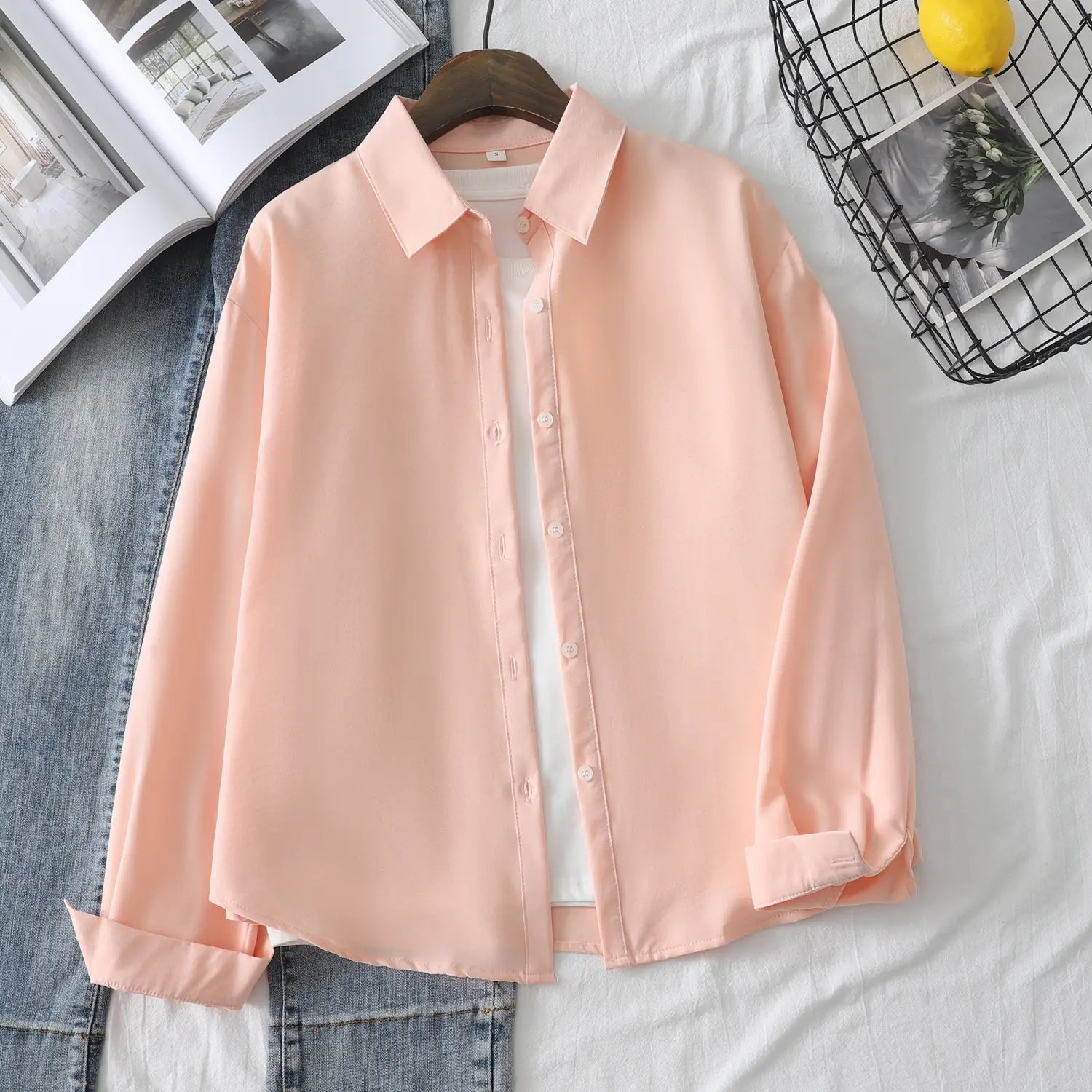 Eine weich pfirsichfarbene Damen-Casualbluse aus Baumwollmischgewebe mit langen Ärmeln mit klassischem Kragen und ordentlich umgeschlagenen Bündchen.