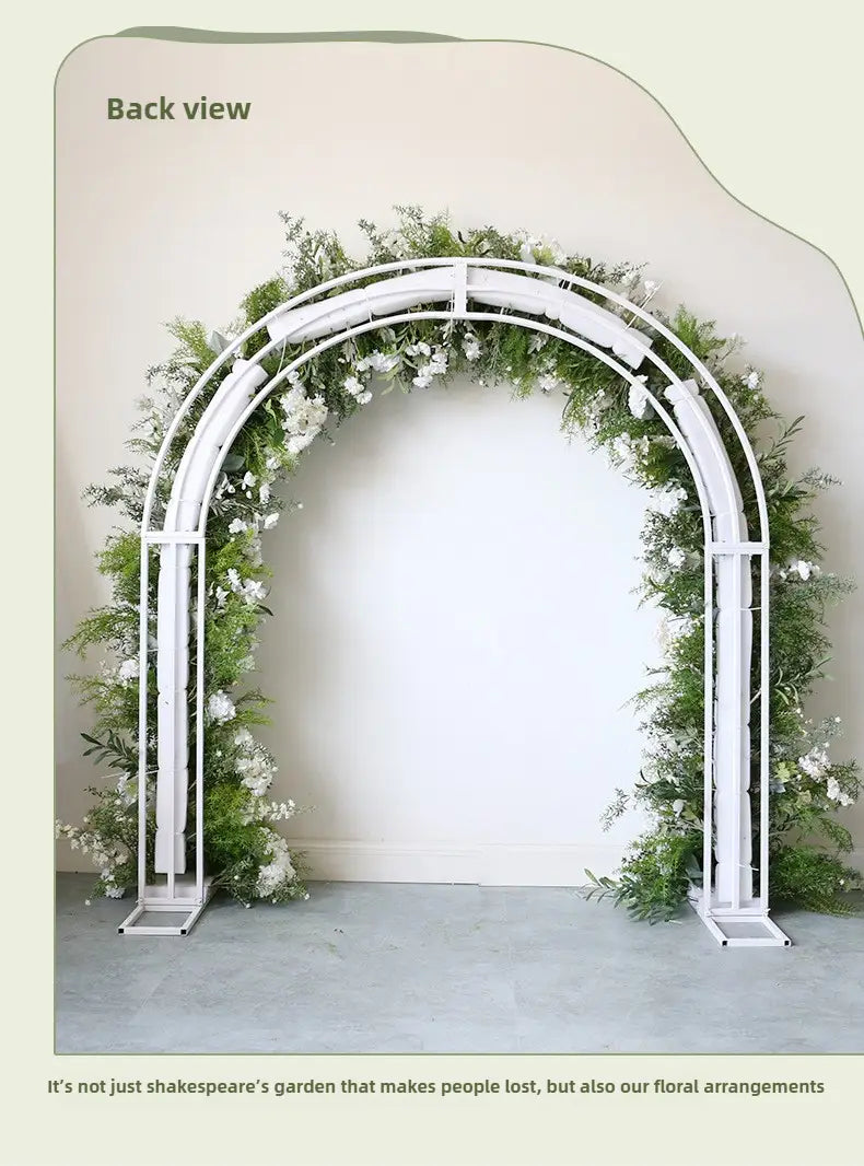 Arco floral metálico blanco para boda con soporte adornado con exuberante vegetación y delicadas rosas blancas artificiales.