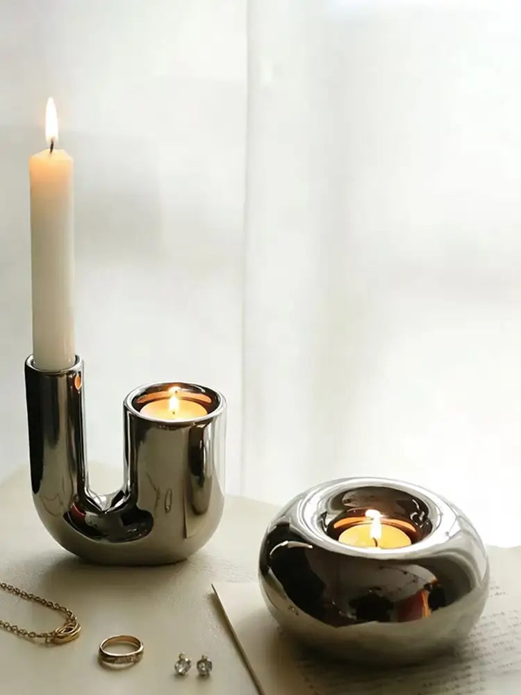 Silver ceramic sphere candle holder set featuring shiny metallic candle holders with sleek modern designs and one u-shaped and two round bases.